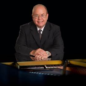 A person in a suit sitting at a piano