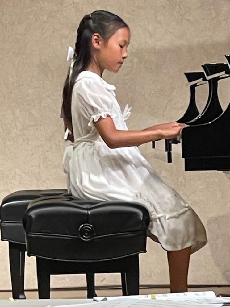 A child in a white dress playing a piano

AI-generated content may be incorrect.